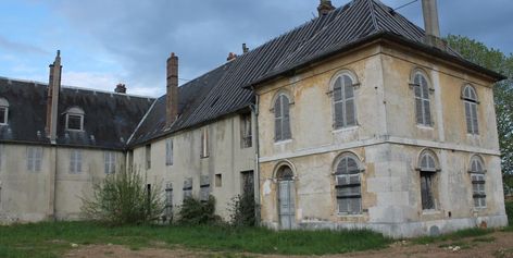 Les Meilleurs Spots Urbex en Normandie à Découvrir Absolument 4 Vue d'une vaste friche industrielle abandonnée envahie par la végétation en Normandie.